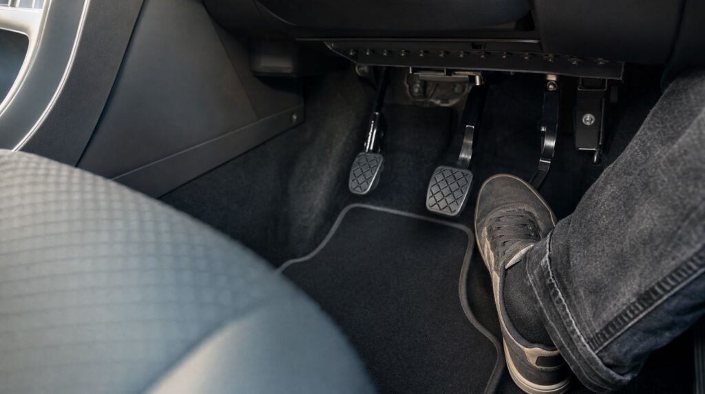 Zusätzliche Pedale auf der Beifahrerseite eines Fahrschulautos, der Fuß des Fahrlehrers ist bereit